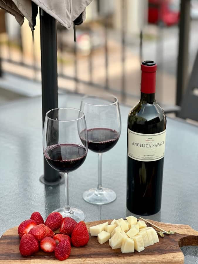 Angélica Zapata con quesos y fresas en una mesa al aire libre